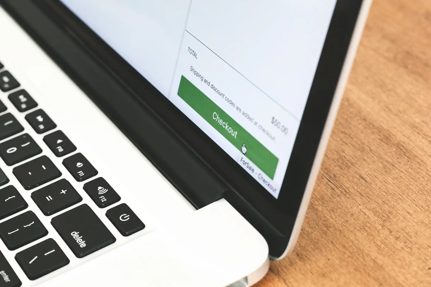 Un laptop bianco con un pulsante “Checkout” verde sul suo schermo.